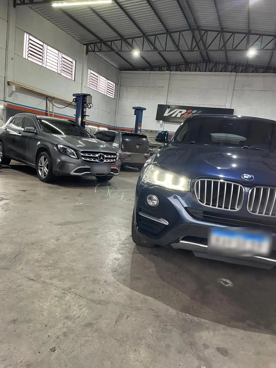 Interior da oficina VR Motors com carros em atendimento, elevadores e o letreiro da empresa