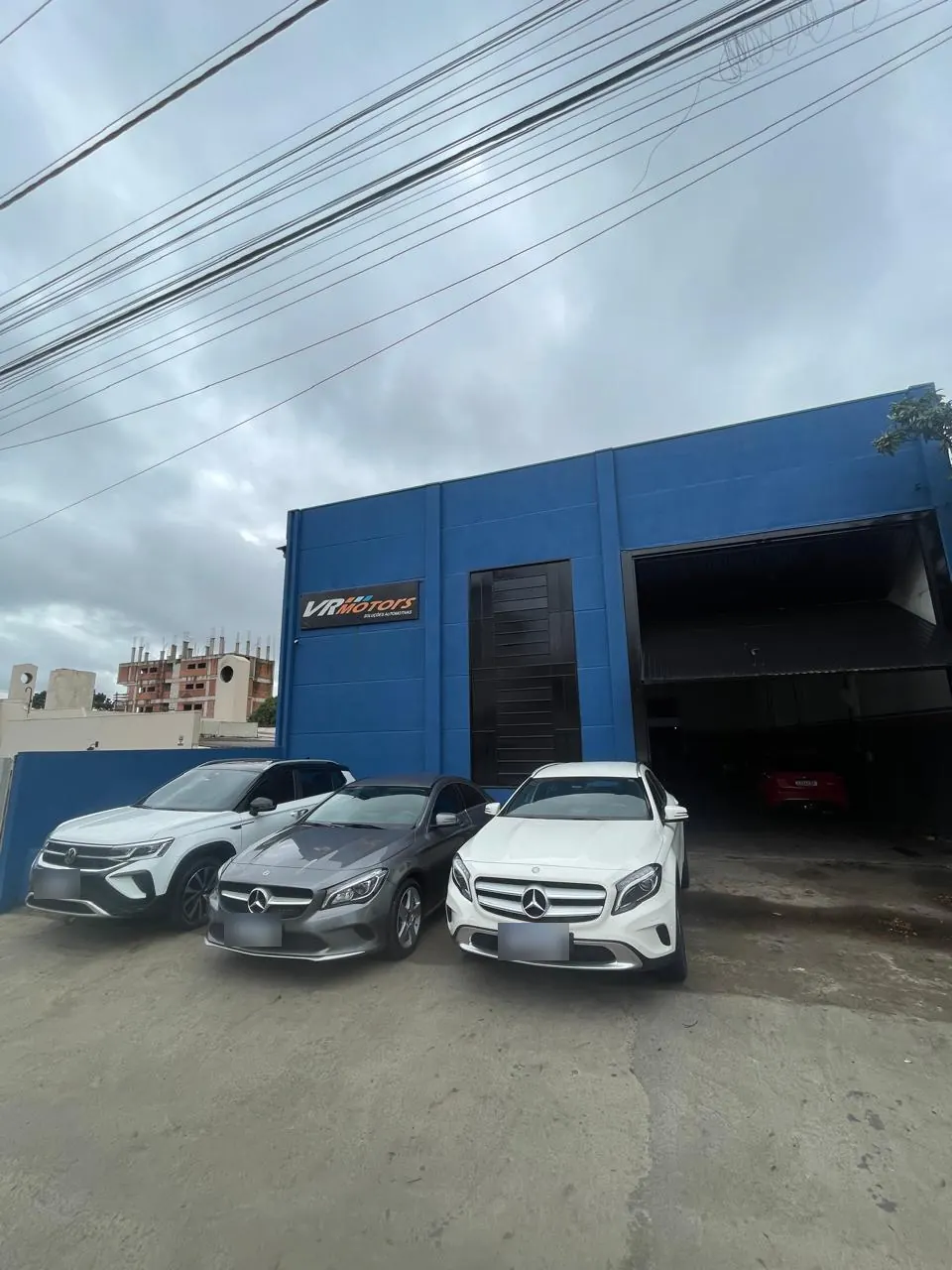 Fachada azul da VR Motors na R. Aquidabam, com carros estacionados na frente